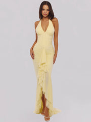 Woman wearing a yellow halter neck dress on a plain background