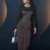 Woman wearing a long sleeve patchwork wrap maxi dress on a runway-style backdrop.