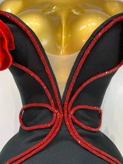 Black dress with red embellishments on a mannequin against a white background