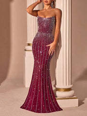 Woman wearing a strapless, sequined evening gown against a classical column background