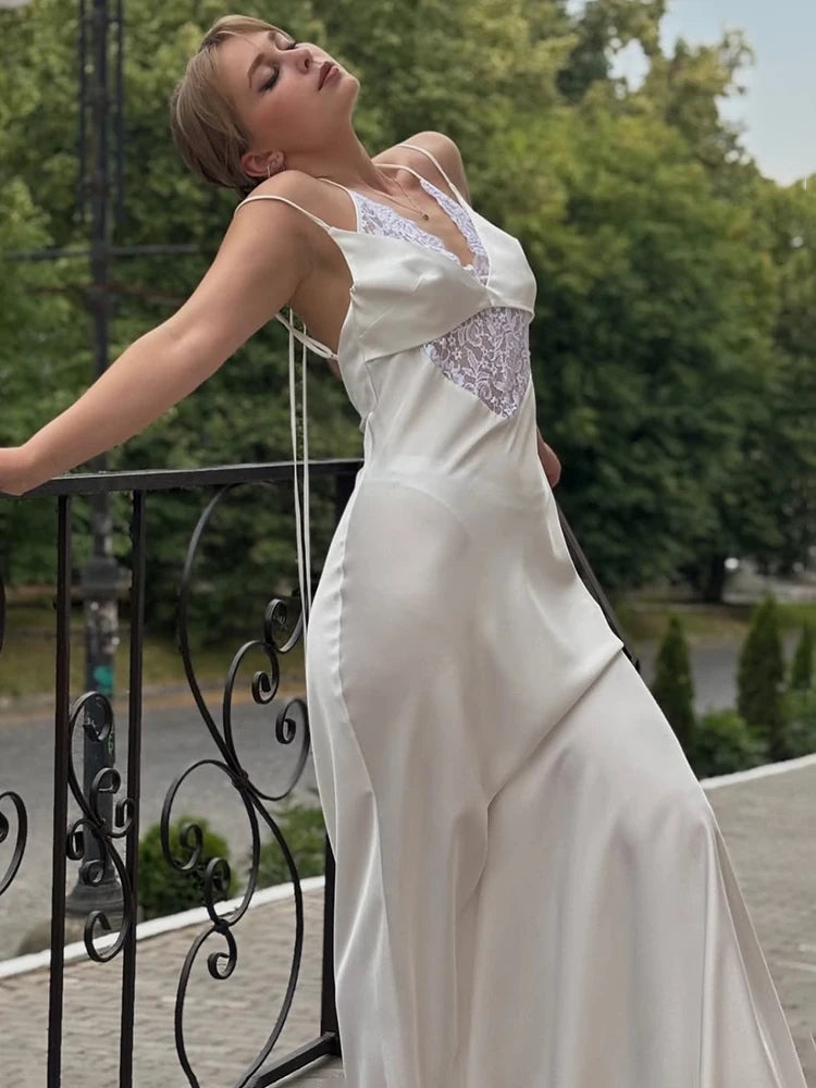 Woman in a white dress standing on a balcony with greenery in the background