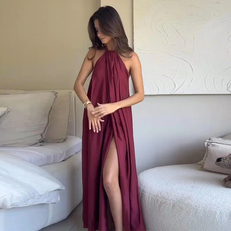 Woman wearing a burgundy halter neck dress with a slit in a modern living room.