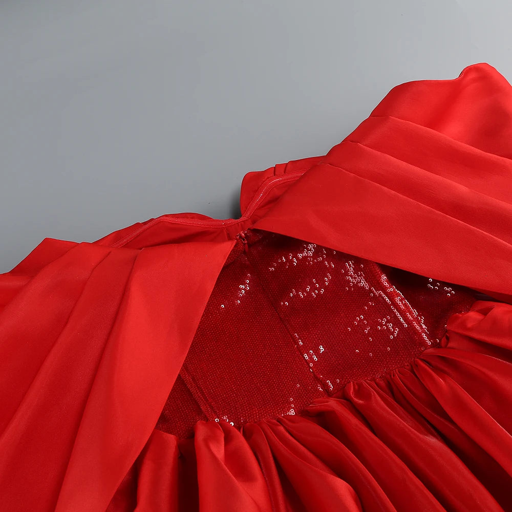Close-up of a red dress with sequin details on a gray background