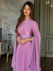 Woman wearing a pink pleated dress in an elegant room.