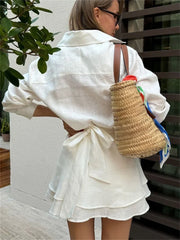 Woman in a white outfit holding a straw bag outdoors