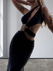 Woman wearing a black dress with cut-out design in a minimal indoor setting