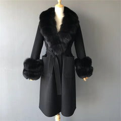 Black coat with fur trim on a mannequin against a plain background