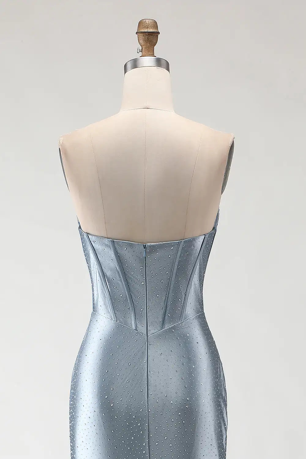 Silver evening gown on a mannequin with a plain background