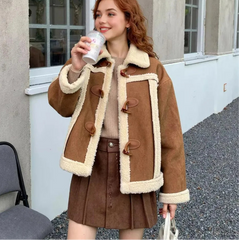Woman wearing a brown coat with white fur trim, holding a cup outdoors.