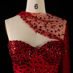 Detail shot of the neckline and embellishments on a red crystal-embellished one-shoulder trumpet gown.