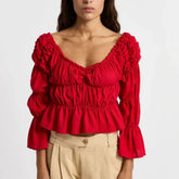 Red ruffled blouse worn by a person on a white background