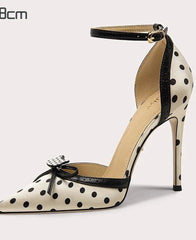Polka dot high-heeled shoe with an ankle strap on a light gray background