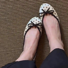 Close-up of feet wearing white polka dot ballet flats with black trim