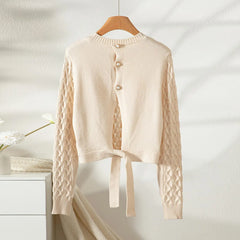 Beige cardigan with cable knit sleeves on a wooden hanger against a white background
