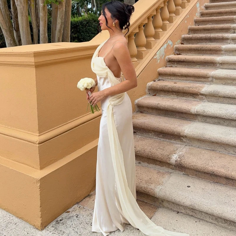 Woman in a white dress standing on a staircase with a yellow wall.