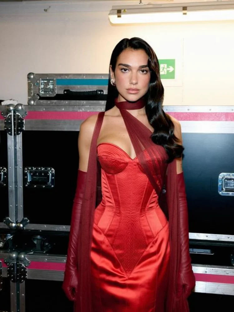 Woman in a red dress standing in front of musical equipment cases.