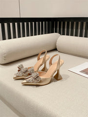 Beige high-heeled shoes with embellishments on a beige surface