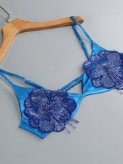 Blue bikini set with floral designs on a hanger against a gray background