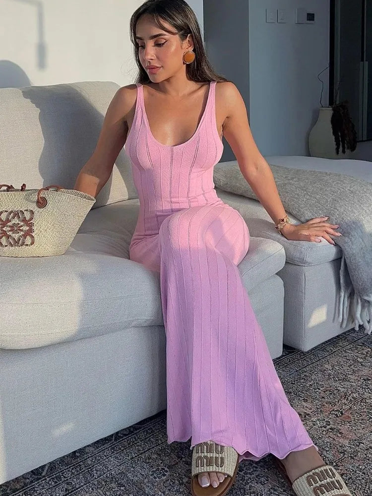 Woman in a pink dress sitting on a couch in a living room.