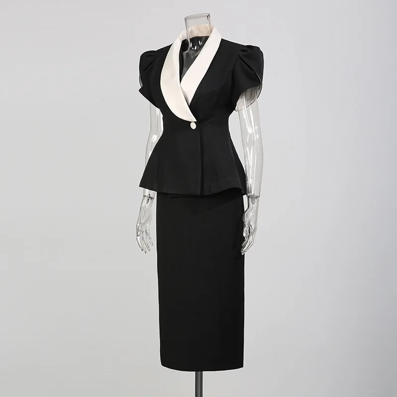 Side view of a black peplum blazer with white contrast lapels and a black midi skirt on a mannequin.