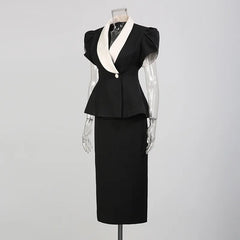 Side view of a black peplum blazer with white contrast lapels and a black midi skirt on a mannequin.