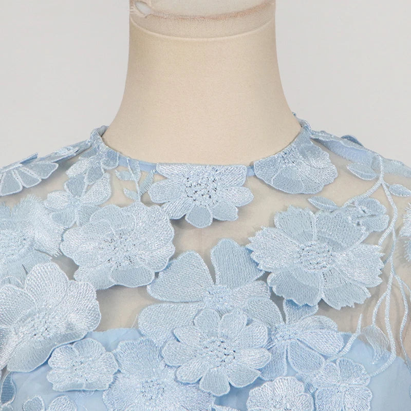 Mannequin wearing a light blue lace dress with floral patterns on a neutral background