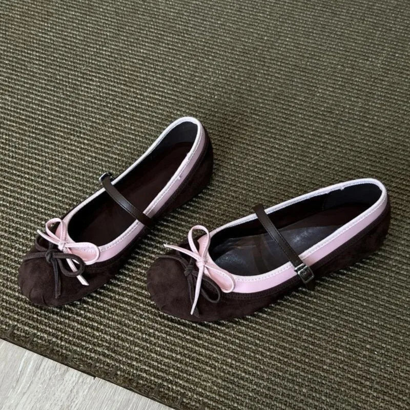 Pair of black and pink flats with bow details on a textured green surface