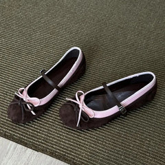 Pair of black and pink flats with bow details on a textured green surface
