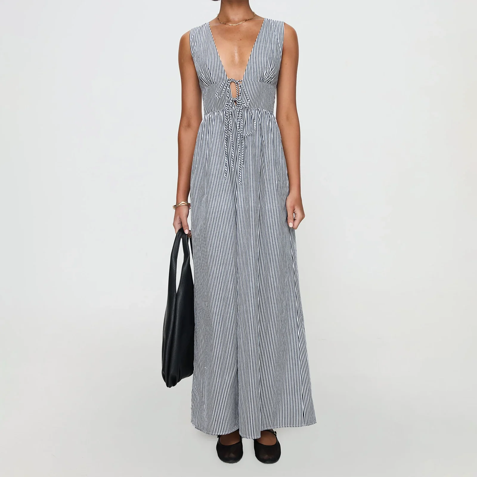 Woman wearing a long blue and white striped dress on a plain background