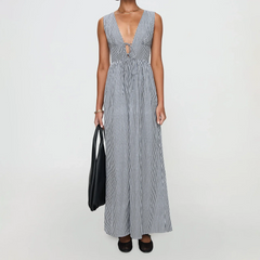 Woman wearing a long blue and white striped dress on a plain background