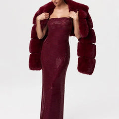 Woman wearing a burgundy strapless dress with a matching fur coat on a white background