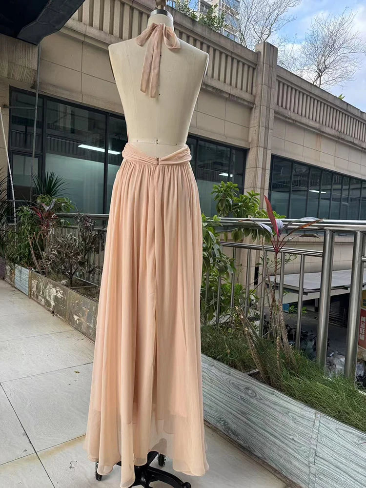 Mannequin wearing a long beige dress on a balcony with plants and building in the background