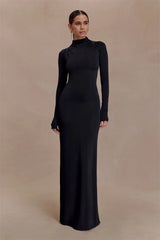 Woman wearing a black long-sleeve gown against a beige background