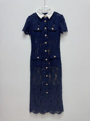 Navy lace dress with gold buttons on a white hanger against a light gray background