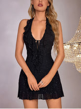 Woman wearing a black sparkly dress with a chandelier in the background