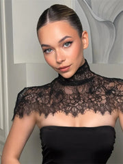 Woman wearing a black lace top against a neutral background