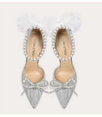 Silver pointed-toe shoes with bow and pearl details on a white background