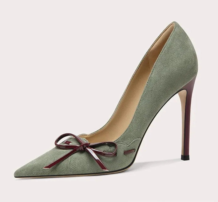 Green high-heeled shoe with a bow on a light gray background