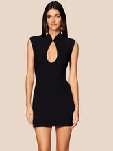 Woman wearing a black dress with a cut-out design on a beige background