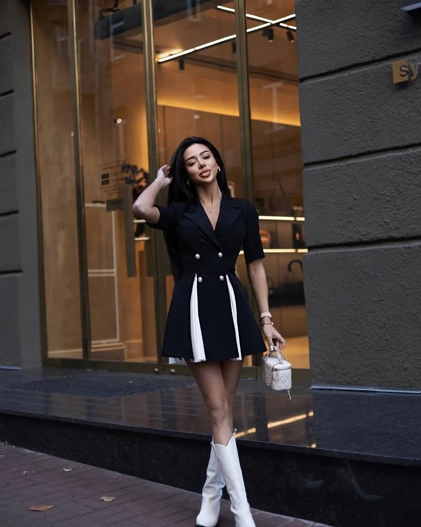 Woman in a black and white dress standing outside a building