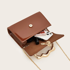 Open brown patent leather evening bag showing interior and chain strap.