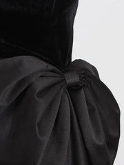 Black dress with a large bow detail on a light gray background