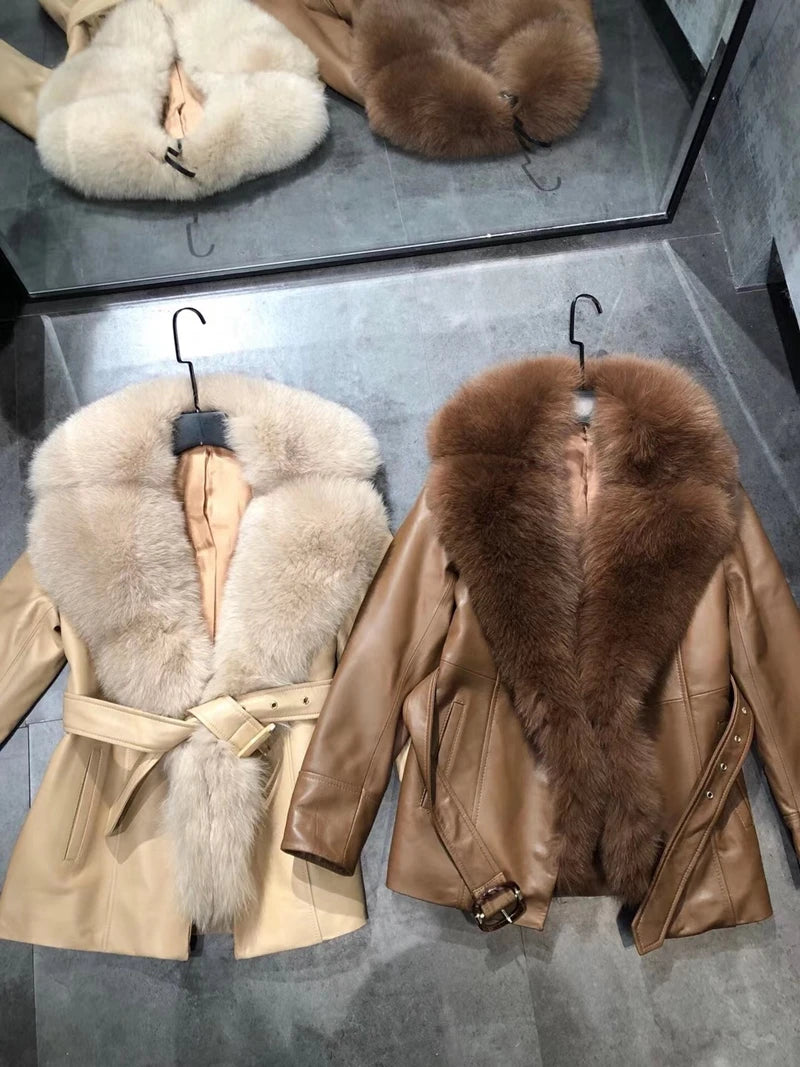 Two leather jackets with fur collars on hangers against a reflective surface.