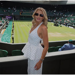 Woman in a polka dot dress standing in front of a tennis court
