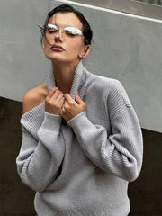 Woman wearing a gray sweater and reflective sunglasses against a neutral background