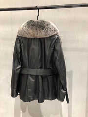 Black leather jacket with fur collar hanging on a rack against a neutral background