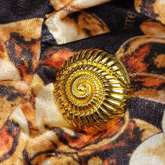 Gold spiral button on a patterned fabric background