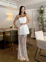 Woman in a white strapless top and lace skirt standing in a modern interior setting.