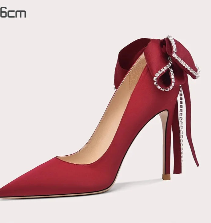 Red high-heeled shoe with decorative bow on a white background