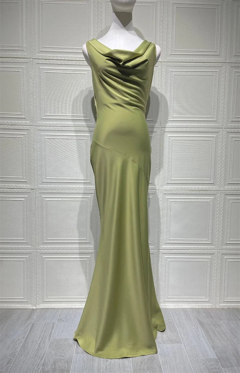 Green evening gown on a mannequin against a white paneled wall.